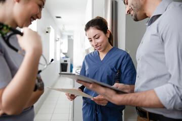 an image of a woman in scrubs holding a clip board surrounded by her peers