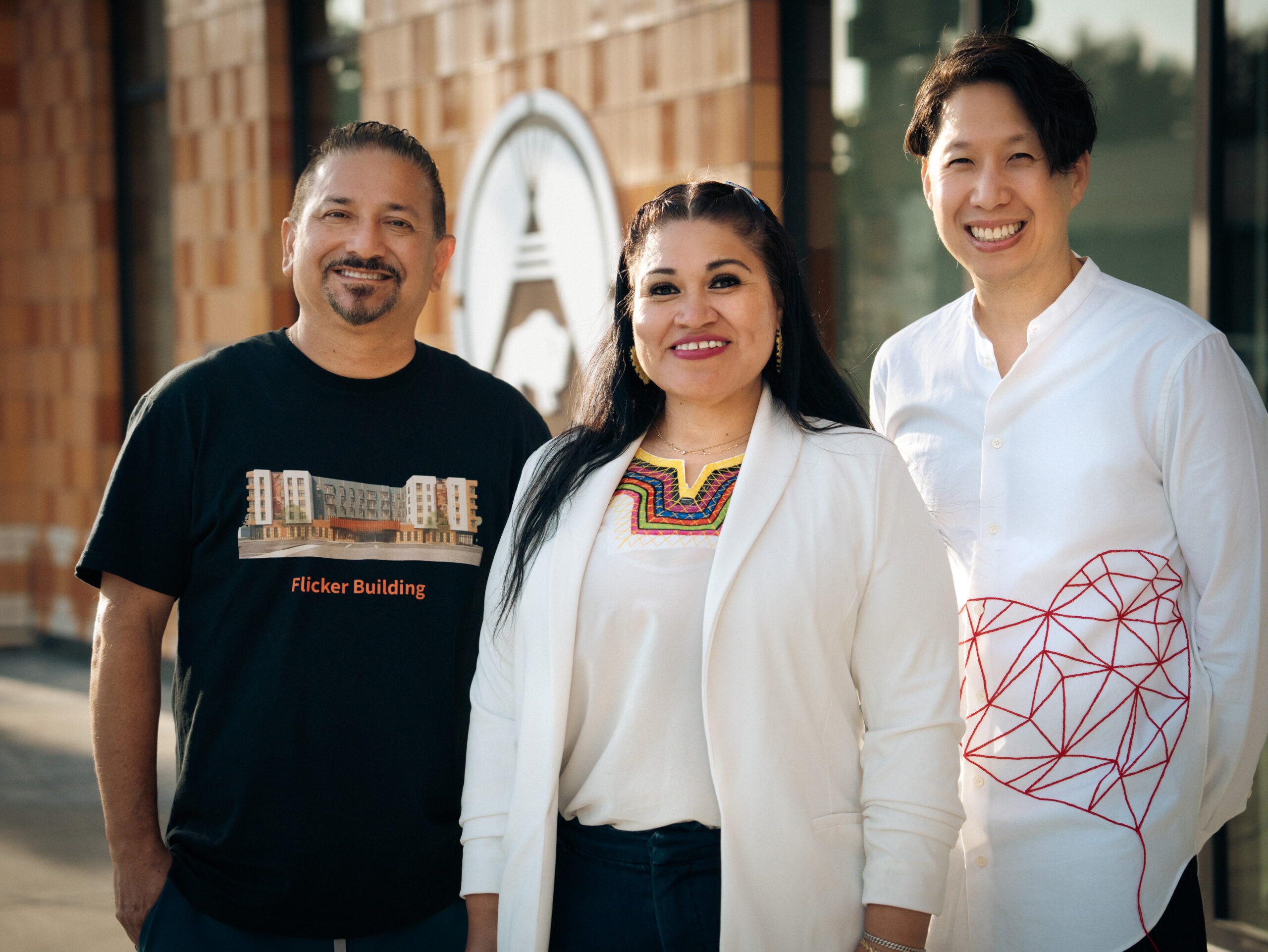 Photo of Native American Health Center Team. Man, Woman, and Man smiling at the camera in front of Dental clinic.